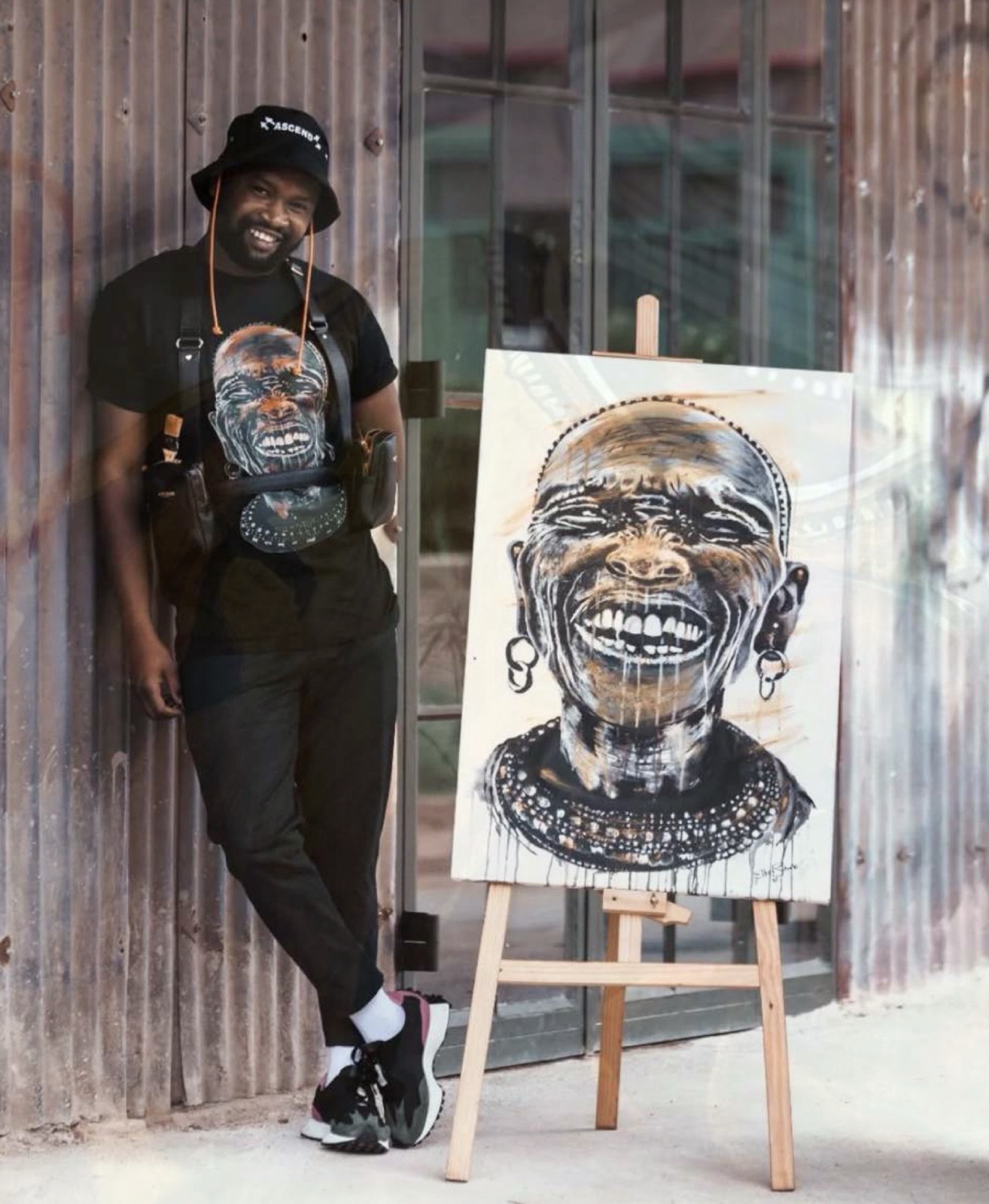 Elliot Sithole standing beside one of his portraits on an easel